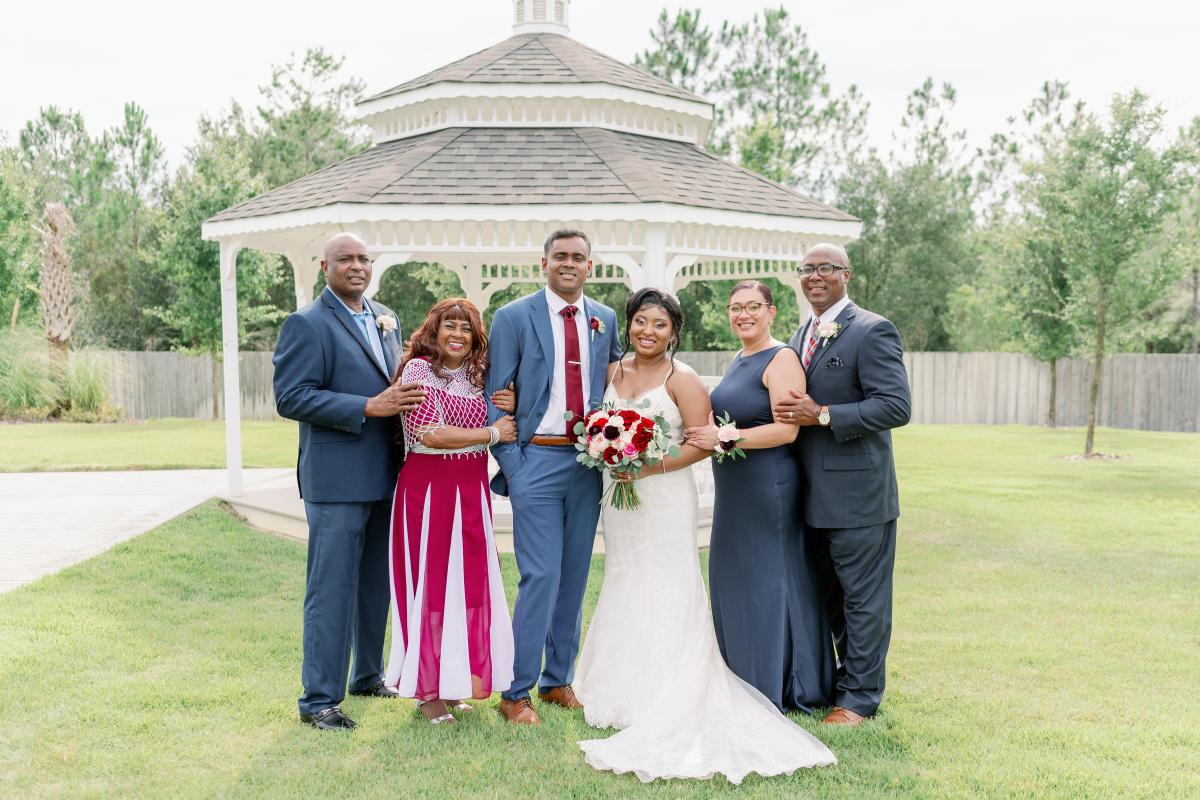 Couple with Both Sides Parents Take Photo in Front of Gazebo